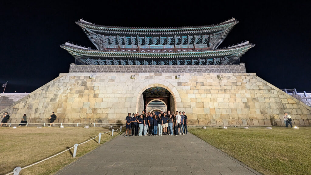 Students posing for a photo in front of a large structure