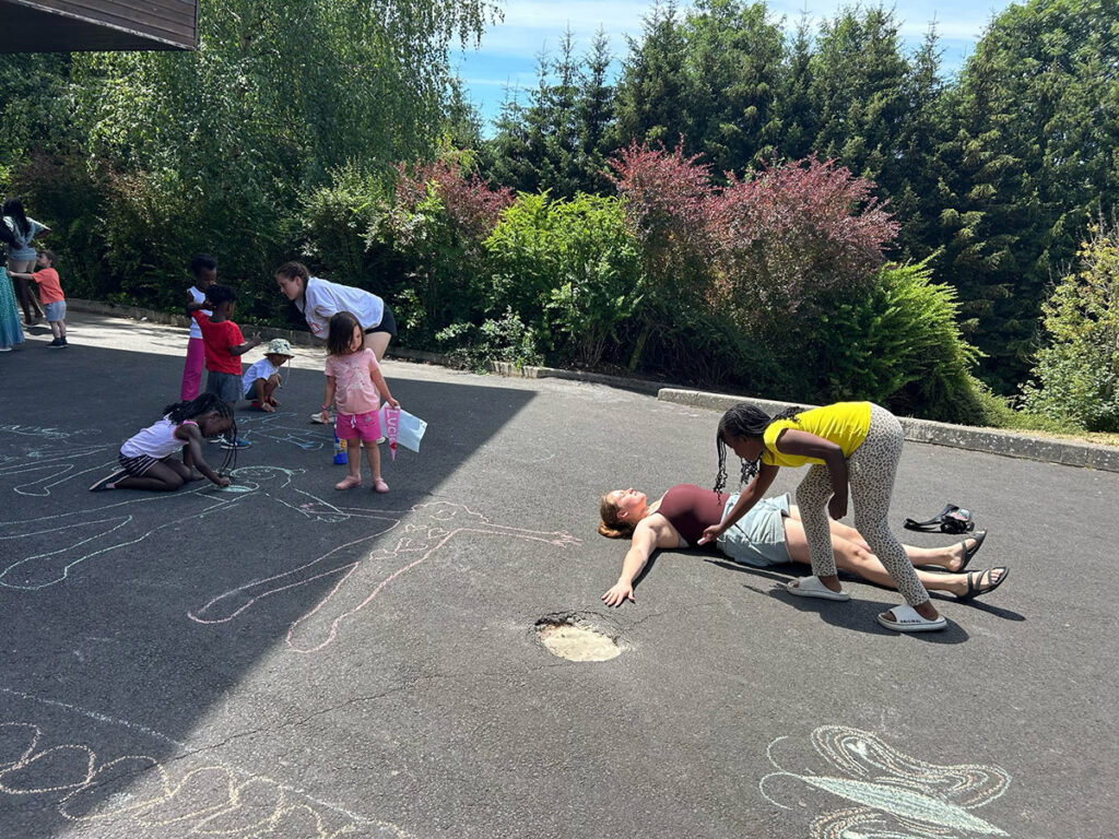 Children drawing chalk outlines of students