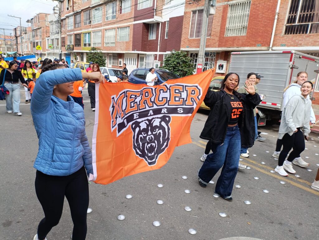 Mercer students walking down a street holding a Mercer Bears flag
